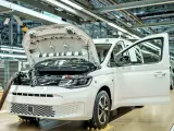 Biały samochód elektryczny na linii produkcyjnej. Widać otwartą maskę i drzwi, a także elementy silnika. Powstają tu polskie samochody.