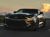 Czarny Chevrolet Camaro pędzi po autostradzie o zachodzie słońca.