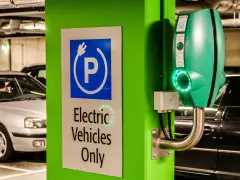 Znak "Tylko pojazdy elektryczne" i zielona ładowarka EVbox. Zastanawiasz się, ile kosztuje ładowanie samochodu elektrycznego w domu?
