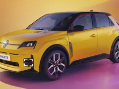 Nowy, żółty Renault 5 z czarnym dachem i czerwonymi akcentami, prezentuje nowoczesny design.