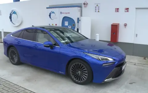 Niebieska Toyota Mirai na stacji wodorowej. Zastanawiasz się nad toyota mirai cena?