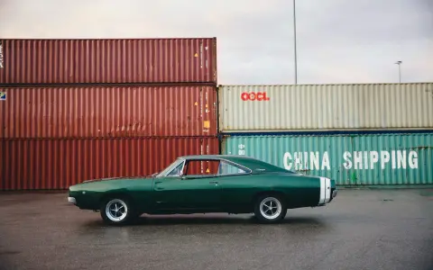 Klasyczne amerykańskie samochody, zielony Dodge Charger z lat 60. na tle kontenerów portowych.