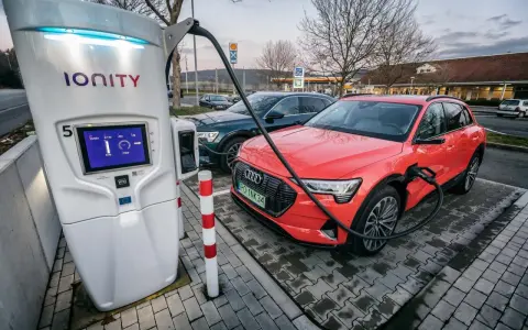 Na stacji Ionity czerwony Audi e-tron ładuje się. Ekran pokazuje 91% naładowania i 77kW mocy. Ile trwa ładowanie samochodu elektrycznego na stacji?