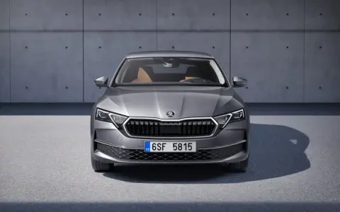 Nowa Skoda Octavia w szarym kolorze, z brązowym wnętrzem, prezentuje się elegancko na tle betonowej ściany.