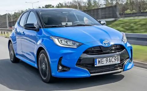 Błękitna, nowa Toyota Yaris z czarnym dachem pędzi po drodze.