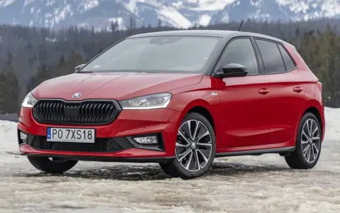 Czerwona Skoda Fabia Monte Carlo z czarnym dachem na tle ośnieżonych gór.