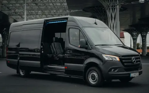 Czarny Mercedes Sprinter z otwartymi drzwiami, wnętrze z wygodnymi fotelami. Zastanawiasz się, ile kosztuje bus do Francji?