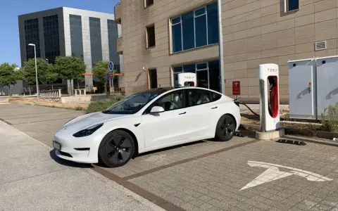 Biały Tesla Model 3, zasilany energią, czeka na ładowanie. Zastanawiasz się, ile koni ma ten model?