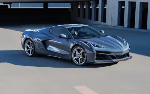 Szary Chevrolet Corvette Stingray z nowoczesnym designem, zaparkowany na tle betonowej architektury.