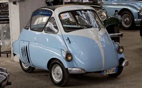 Urocze, błękitno-białe BMW Isetta z lat 50. z charakterystycznymi drzwiami z przodu, gotowe na przejażdżkę po mieście.