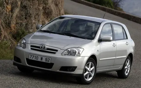 Srebrna Toyota Corolla E12 na krętej drodze, z kamienistym zboczem w tle.