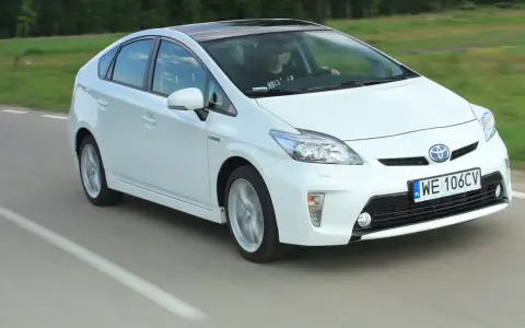 Biała Toyota Prius w ruchu. Czy warto kupić ten hybrydowy samochód?