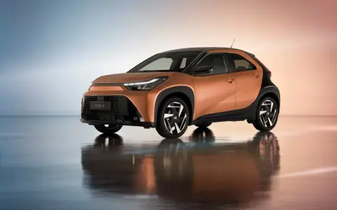 Pomarańczowa Toyota Aygo X z czarnymi dodatkami, idealna do miasta. Sprawdź atrakcyjną toyota hybryda cena.