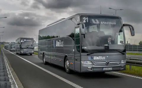 Szary bus UniBus z numerem 21 jedzie autostradą. To jeden z wielu pojazdów na trasie Kraków-Katowice.