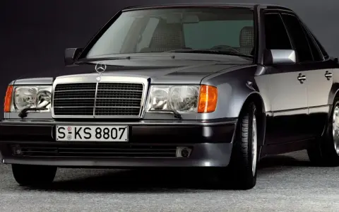 Klasyczny youngtimer, szary Mercedes-Benz W124 z charakterystyczną kratką i reflektorami.
