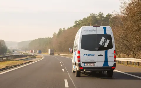 Biały bus AR-SPEED jedzie autostradą. Zastanawiasz się, ile kosztuje bus do Niemiec? Sprawdź na ar-speed.pl.