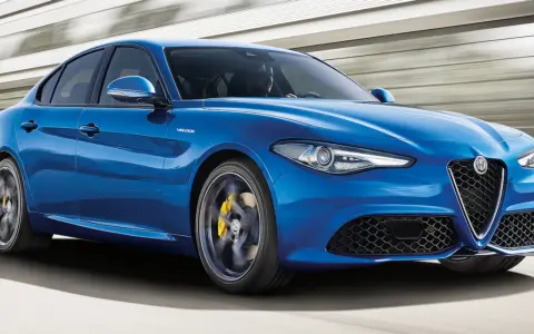 Błękitne Alfa Romeo Giulia Veloce pędzi po drodze, ukazując sportowy charakter i dynamiczną sylwetkę.