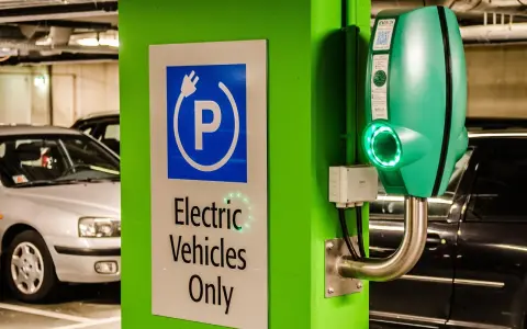 Znak "Tylko pojazdy elektryczne" i zielona ładowarka EVbox. Zastanawiasz się, ile kosztuje ładowanie samochodu elektrycznego w domu?
