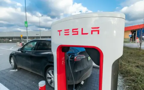 Czarna Tesla podłączona do ładowarki. Zastanawiasz się, ile kosztuje ładowanie Tesli? To zależy od taryfy i lokalizacji.