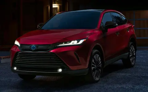 Elegancka, czerwona Toyota Venza z nowoczesnymi światłami LED stoi przed domem o zmierzchu.