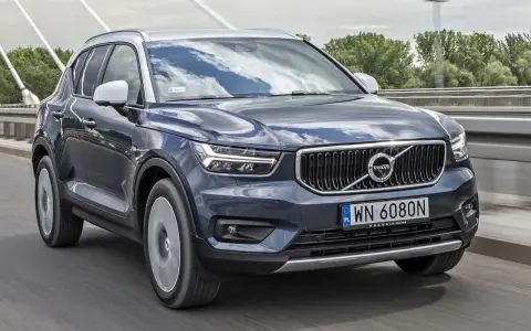 Ciemnogranatowy Volvo XC40 jedzie po moście. Sprawdź aktualną volvo xc40 cena i ofertę.