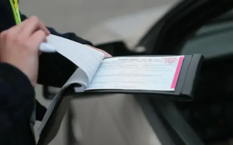 Policjant wypisuje mandat za kolizję. Dokument zawiera numer seryjny i pieczęć.