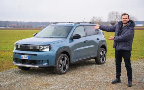 Mężczyzna prezentuje nowy, niebieski Fiat Grande Panda na tle zielonego pola.