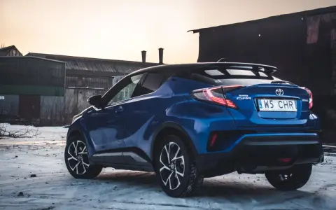 Niebieska Toyota C-HR Hybrid na tle opuszczonych budynków. Czy wybrać hybrydę czy benzynę?