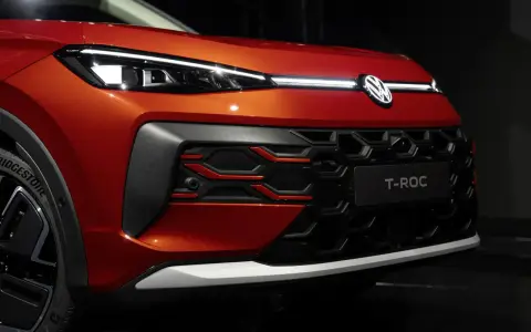Nowy VW T-Roc w kolorze pomarańczowym prezentuje się z przodu z charakterystycznym grillem i nowoczesnymi światłami IQ.LIGHT.