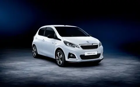 Biały Peugeot 108 GT Line stoi na ciemnym tle.
