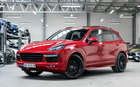 Czerwony Porsche Cayenne GTS lśni w salonie, gotowy na podbój dróg.