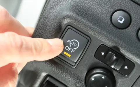 Palec naciska przycisk "AUTO OFF", wyłączając system start-stop.