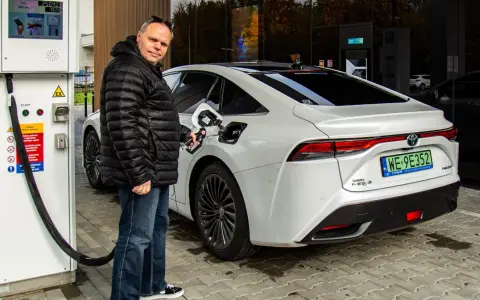 Mężczyzna tankuje białą Toyotę Mirai na jednej z pierwszych stacji wodorowych w Polsce.