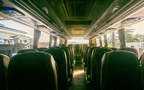 Wnętrze autobusu z rzędami zielonych siedzeń. Trudno ocenić, ile bus ma miejsc, ale wygląda na to, że jest ich sporo.