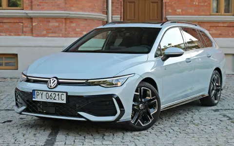 Jasny VW Golf 8 Variant na brukowanej ulicy przed ceglanym budynkiem. Elegancki kombi z nowoczesnym designem.