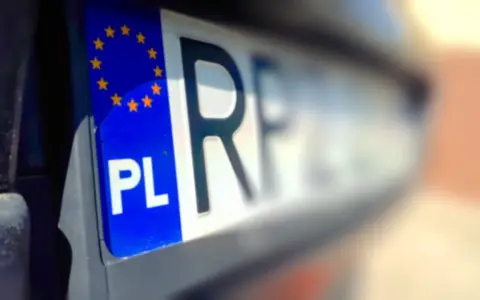 Zbliżenie na polską tablicę rejestracyjną z symbolem UE. Litery "PL" i fragment numeru rejestracyjnego są wyraźne.