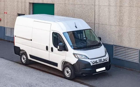 Biały bus 9 osobowy Fiat Ducato, zaparkowany przy betonowej ścianie. Zastanawiasz się, ile pali bus 9 osobowy?