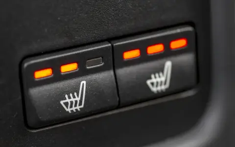 Dwa przyciski z ikonami siedzenia i świecącymi na czerwono wskaźnikami. Tak działają podgrzewane fotele.
