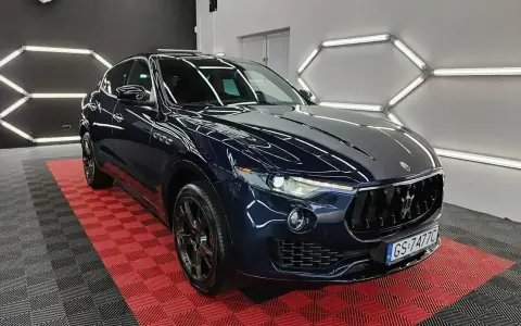 Lśniący, granatowy Maserati Levante na czerwono-czarnej podłodze. Sprawdź aktualną maserati levante cena i poczuj luksus.