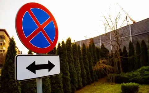 Znak zakaz parkowania z tabliczką wskazującą kierunki.
