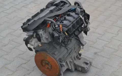 Silnik Alfa Romeo 156, gotowy do montażu. Widoczny koło zamachowe i elementy układu dolotowego.