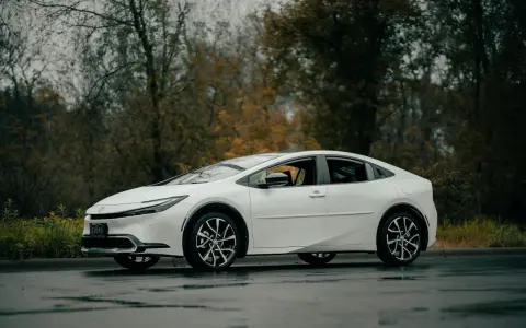 Biała Toyota Prius na mokrej drodze. Zastanawiasz się, ile wytrzymuje bateria w hybrydzie Toyoty?