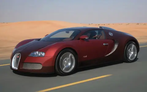 Czerwone Bugatti Veyron sunie po pustynnej drodze. Zastanawiasz się, ile kosztuje taki luksus?