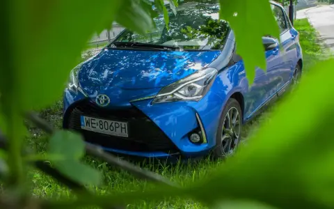 Niebieski Toyota Yaris Hybrid. Czy warto? Zobacz auto z bliska, ukryte wśród zieleni.