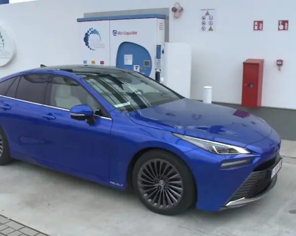 Niebieska Toyota Mirai na stacji wodorowej. Zastanawiasz się nad toyota mirai cena?