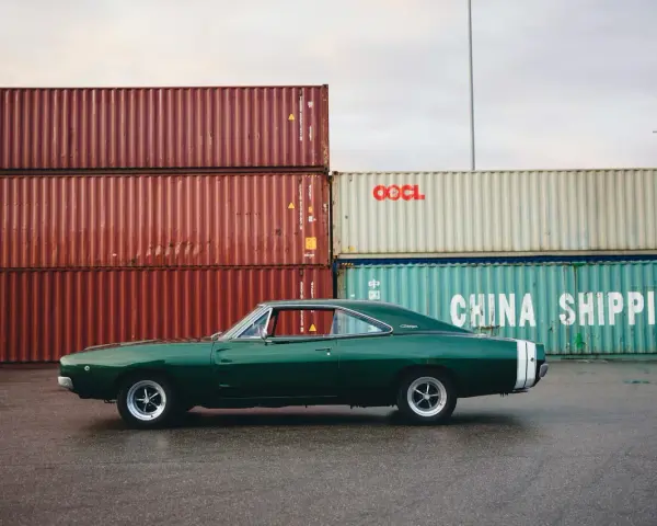 Klasyczne amerykańskie samochody, zielony Dodge Charger z lat 60. na tle kontenerów portowych.