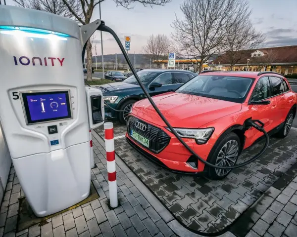 Na stacji Ionity czerwony Audi e-tron ładuje się. Ekran pokazuje 91% naładowania i 77kW mocy. Ile trwa ładowanie samochodu elektrycznego na stacji?