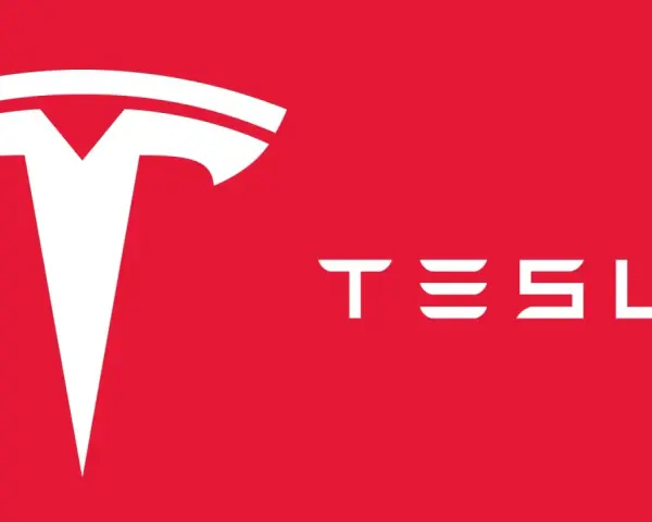 Biały, stylizowany symbol litery "T" i napis "TESLA" na czerwonym tle. Tak wygląda znaczek Tesli.