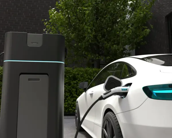 Biała Tesla ładuje się przy nowoczesnej stacji. Wyświetlacz pokazuje "CHARGING 100%", odpowiadając na pytanie, jak długo ładuje się Tesla.