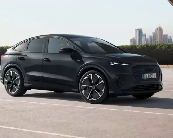 Elegancki, czarny Audi Q4 e-tron, elektryk z dynamiczną linią nadwozia, zaparkowany na tle nowoczesnej panoramy miasta.